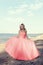 Young blonde woman at the beach with red tulle ball dress