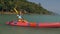 Young blonde woman in blue swimsuit rows pink plastic canoe along azure sea bay past island with palms under blue sky at