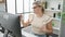 Young blonde woman business worker using computer stretching arms relaxing at the office