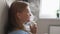 Young blonde woman doing inhalation with steam nebulizer at home. Asthma, flu, health care concept.