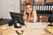 Young blonde woman ecommerce business worker boring sitting on the table at office