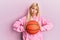 Young blonde woman holding basketball ball skeptic and nervous, frowning upset because of problem