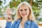 Young blonde woman holding english banknotes pounds, showing money smiling happy and confident outdoors