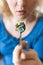 Young blonde woman holding a full spoon of assorted pills in front of her open mouth