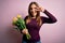 Young blonde woman holding romantic bouquet of yellow tulips flowers over pink background Doing peace symbol with fingers over