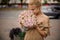 Young blonde woman holds bouquet of roses and sniffs it.