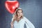 Young blonde woman holds a heart-shaped balloon