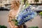 Young blonde woman holds large bouquet of delphinium in her hands and looks away