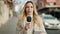 Young blonde woman journalist speaking using microphone at street