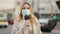 Young blonde woman journalist wearing medical mask speaking using microphone at street