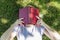 A young blonde woman lies in a park on the grass with her face covered in a book. Summer sunny day. Top view. Relaxation in nature