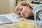 Young blonde woman lies with popcorn on the bed and watches a movie on a laptop