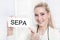 Young blonde woman looking at camera holding a SEPA sign
