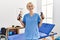 Young blonde woman physiotherapist smiling confident holding press hand tool at rehab clinic