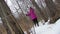 Young blonde woman in pink coat walking in winter forest