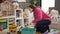 Young blonde woman preschool teacher collecting toys at kindergarten