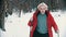 A young blonde woman in red down jacket walking on ski in the forest - winter activities