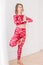 Young blonde woman in red ethnic costume practicing yoga tree pose asana Namaste in home or light studio