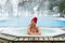 Young blonde woman in red hut in bathtub jacuzzi outdoors at winter