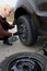 A young blonde woman removes the wheel with a key near her car with a flat tire