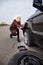 A young blonde woman removes the wheel with a key near her car with a flat tire