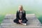 Young blonde woman sitting in pose of lotos on pier in autumn on background of lake