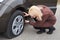 A young blonde woman stands near her car with a flat tire