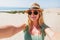 Young blonde woman taking selfie on the beauty sandy beach.