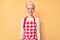 Young blonde woman with tattoo wearing professional baker apron with a happy and cool smile on face