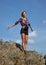 Young blonde woman tourist in shirt and shorts on a cliff on b