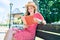 Young blonde woman on vacation reading book sitting on bench at the park