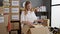 Young blonde woman volunteer packing clothes on cardboard smiling at charity center