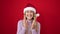 Young blonde woman wearing christmas hat clapping hands applause over isolated red background