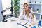 Young blonde woman wearing dentist uniform talking on the telephone holding xray at clinic