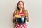 Young blonde woman wearing professional baker apron holding cooking pot with spaghetti sticking tongue out happy with funny