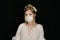Young blonde woman in white dress and face respirator mask