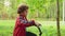 Young boy bicyclist riding on bicycle on path in green summer park. Curly boy cycling on bicycle in city park. Summer