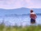 Young boy in blue swimming shorts stay in cold water of lake