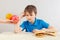 Young boy in blue at the table chooses between fastfood and fruits