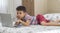 Young boy child lying on bed using a laptop. Online class lesson on video. Distant remote education. New normal school study. Kids