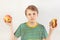 Young boy chooses between fastfood and fresh apple on white background