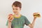 Young boy chooses between fastfood and fruit on white background