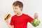 Young boy chooses between fastfood and vegetable on white background