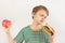 Young boy chooses between hamburger and apple on white background