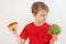 Young boy chooses between hamburger and broccoli on white background