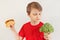 Young boy chooses between hamburger and vegetable on white background