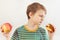 Young boy chooses between sandwich and fruit on white background