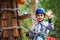 Young boy climbing pass obstacles in rope. Child in forest adventure park