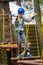 Young boy climbing pass obstacles in rope. Child in forest adventure park