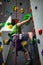 Young boy climbing up on practice wall in indoor rock gym